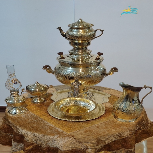 نمای کامل از ست ۴ تکه شامل سماور، پارچ، قوری، سینی و جام طلایی با قلمزنی طلایی، نمایش هماهنگی و زیبایی کلی.
